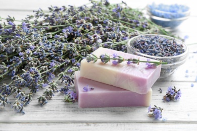 Handmade soap bars with lavender flowers on white wooden table. Space for text
