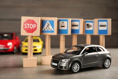 Many different miniature road signs and car on grey table. Driving school