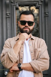 Photo of Portrait of handsome stylish man in sunglasses near door outdoors