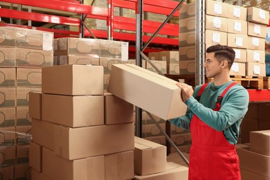 Worker stacking cardboard boxes in warehouse. Wholesaling