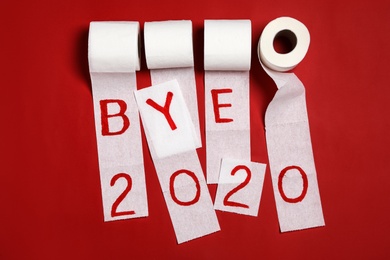 Toilet paper with text Bye 2020 on red background, flat lay