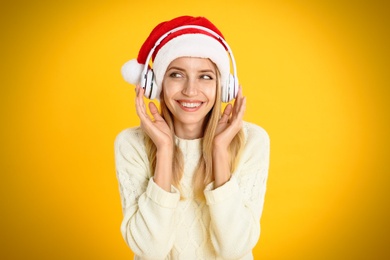 Happy woman with headphones on yellow background. Christmas music