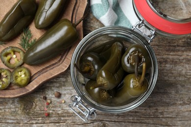 Photo of Pickled green jalapeno peppers on wooden table, flat lay