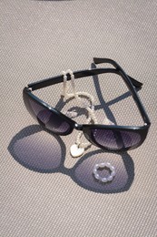 Stylish sunglasses and jewelry on grey surface