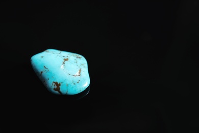Photo of Beautiful turquoise gemstone on black background. Space for text