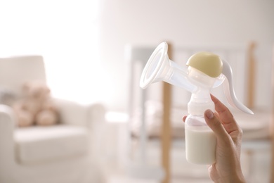 Closeup view of woman holding manual breast pump indoors, space for text. Baby health