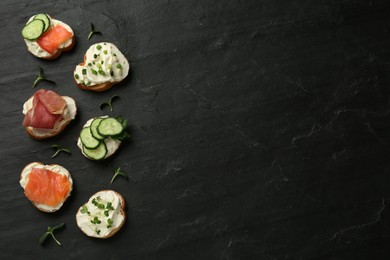 Photo of Delicious sandwiches with cream cheese and other ingredients on black table, flat lay. Space for text