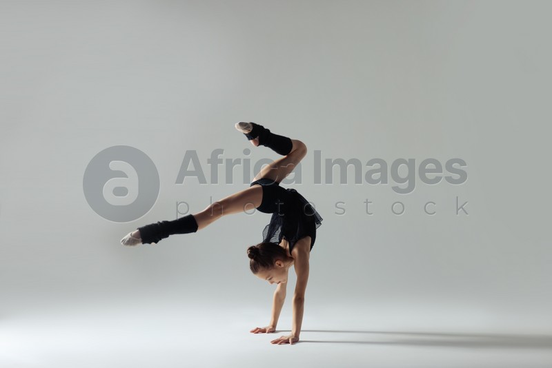 Cute little gymnast doing handstand on white background