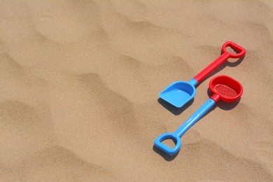 Photo of Plastic shovel and sieve on sand, space for text. Beach toys