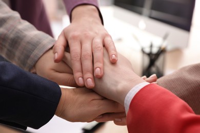 Women holding hands together in office, closeup