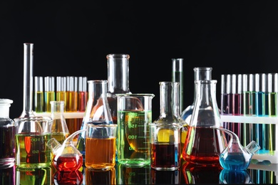 Laboratory glassware with colorful liquids on black background