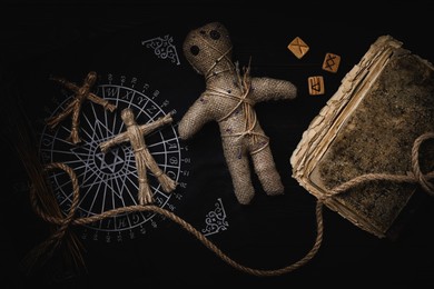 Voodoo doll with pins surrounded by ceremonial items on table, flat lay