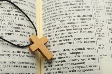 MYKOLAIV, UKRAINE - DECEMBER 20, 2021: Christian cross on open Bible, closeup view