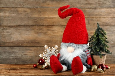 Cute Christmas gnome and festive decor on table against wooden background. Space for text