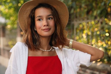 Portrait of beautiful stylish young woman in straw hat on city street