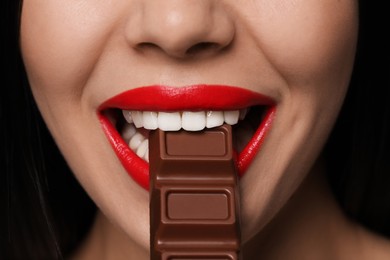 Young woman with red lips eating chocolate, closeup