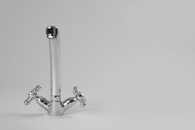 Double handle water tap on grey background. Space for text