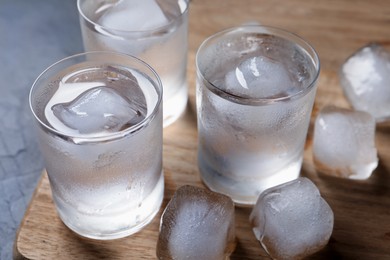 Shot glasses of vodka with ice cubes on table, closeup