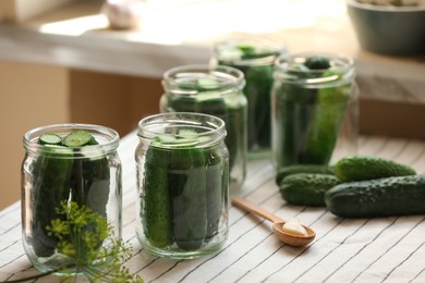 Photo of Glass jars with fresh cucumbers and other ingredients on table. Canning vegetables