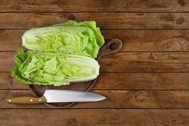 Halves of fresh ripe Chinese cabbage and knife on wooden table, flat lay. Space for text