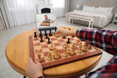 Woman playing chess with partner via online video chat at table indoors, closeup