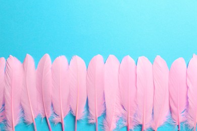 Beautiful pink feathers on light blue background, flat lay. Space for text