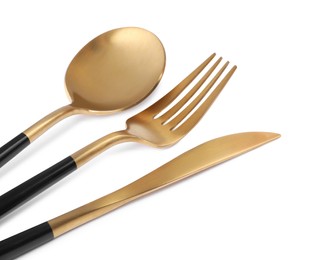 Photo of New golden cutlery with black handles on white background, closeup