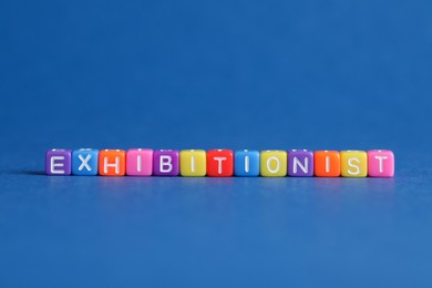 Photo of Word EXHIBITIONIST made with colorful cubes on blue background