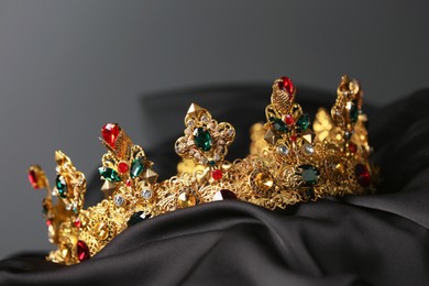 Photo of Beautiful golden crown with gems on dark cloth
