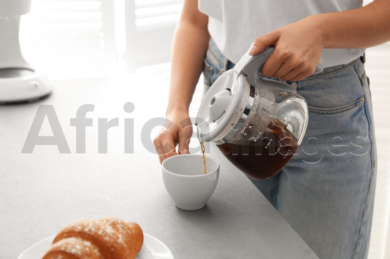 Woman pouring coffee into cup at home, closeup. Morning routine