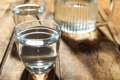 Glass of water on wooden table, closeup. Refreshing drink