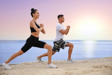 Couple doing yoga exercise together on beach at sunrise