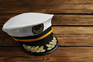 Peaked cap with accessories on wooden background, space for text