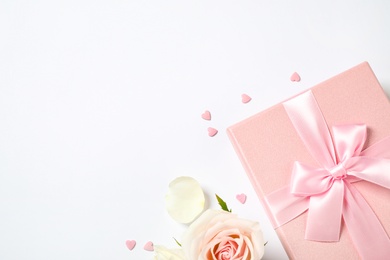 Pink gift box and beautiful flower on white background, flat lay. Space for text