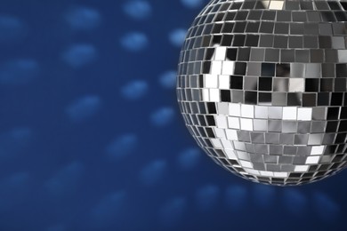 Shiny disco ball on blue background, closeup. Space for text