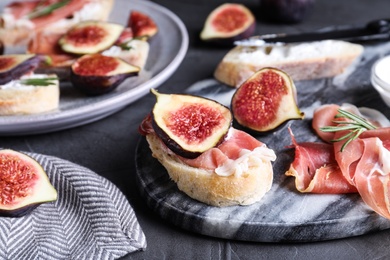 Sandwich with ripe fig, cream cheese and prosciutto served on black table, closeup