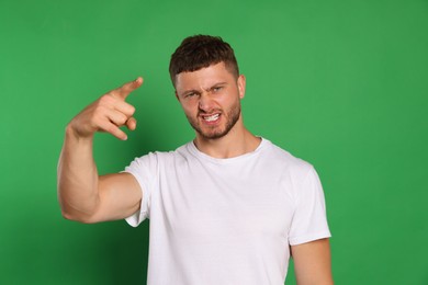 Aggressive young man pointing on green background