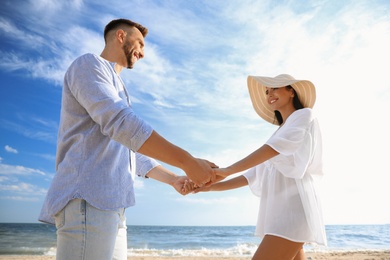 Happy couple holding hands on beach, low angle view
