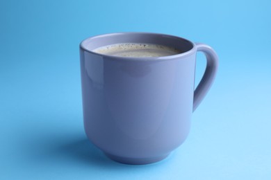 Mug of freshly brewed hot coffee on light blue background