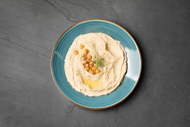 Plate of tasty hummus with garnish on black table, top view