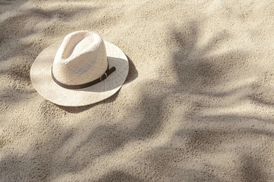 Photo of Stylish straw hat on sand outdoors, space for text
