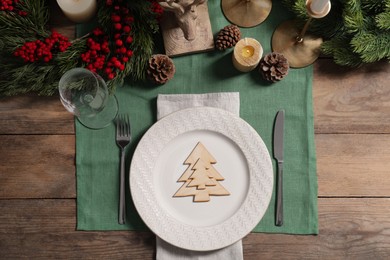 Photo of Festive place setting with beautiful dishware, cutlery and decor for Christmas dinner on wooden table, flat lay