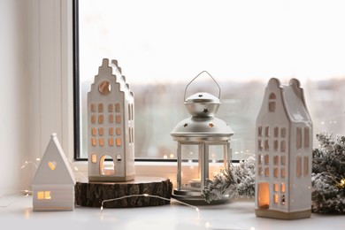 Photo of Beautiful house shaped candle holders and Christmas decor on windowsill indoors