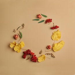 Dried flowers, leaves and berries arranged in shape of wreath on beige background, flat lay with space for text. Autumnal aesthetic