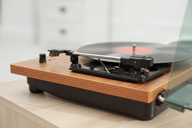 Turntable with vinyl record on table against blurred background, closeup