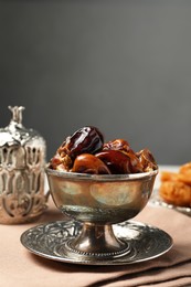 Photo of Tea and date fruits served in vintage tea set on white table, space for text