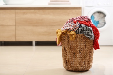 Wicker basket with dirty clothes on floor in bathroom. Space for text