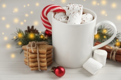 Composition with delicious marshmallow cocoa and Christmas decor on white wooden table