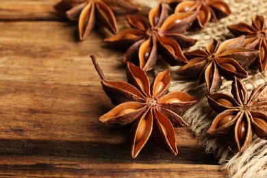 Aromatic anise stars on wooden table, closeup. Space for text
