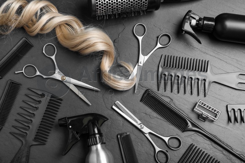 Flat lay composition of professional scissors, hair strand and other hairdresser's equipment on black table. Haircut tool